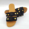 Black sandal with gold floral embellishments on a white background