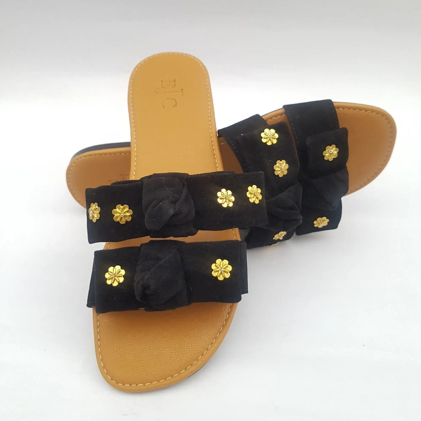Black sandal with gold floral embellishments on a white background