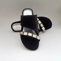 Black sandals with rhinestone embellishments on a light gray background