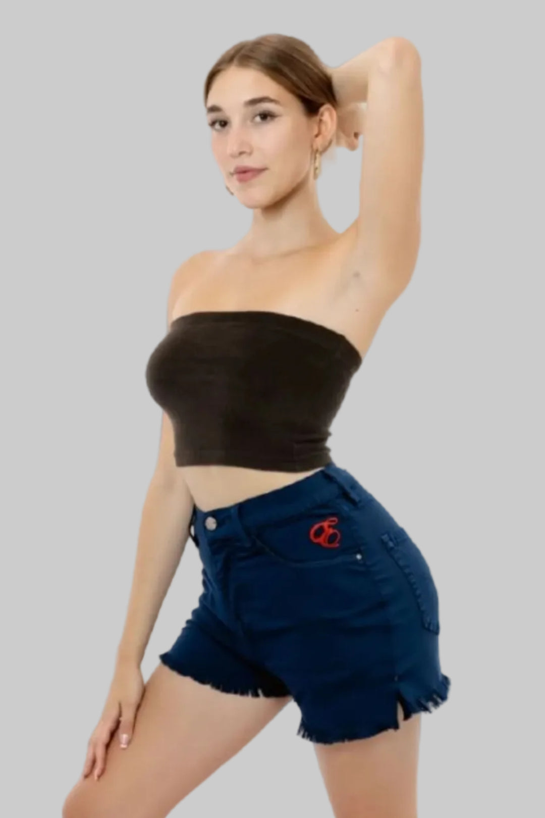 Woman wearing a white strapless top and navy denim shorts on a beige background with Element Jeans Co branding.