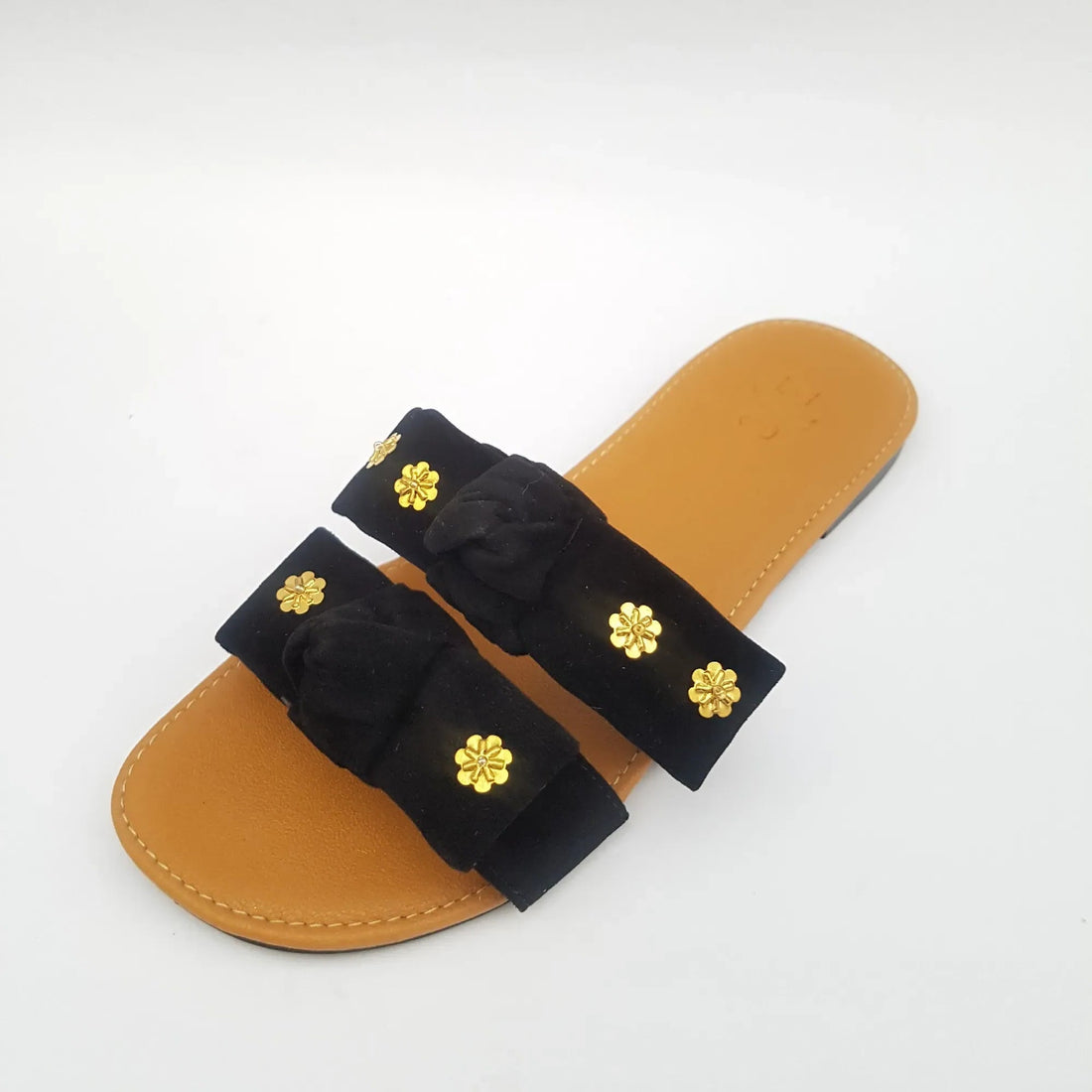 Pair of sandals with black straps and gold flower embellishments on a white background