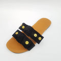 Black sandal with gold floral embellishments on a white background