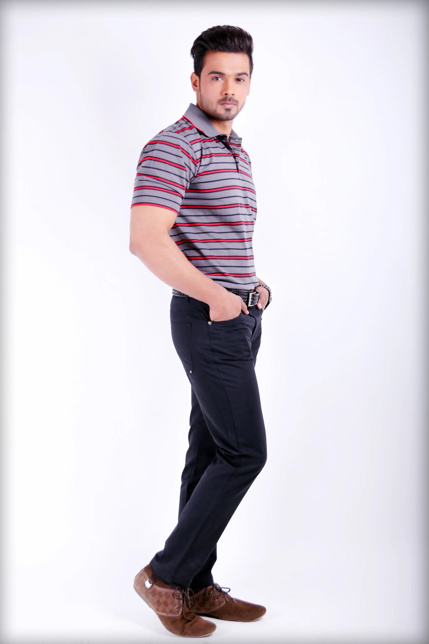 Man wearing a striped polo shirt and dark pants on a white background