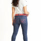 Woman wearing blue jeans with red accents on a white background