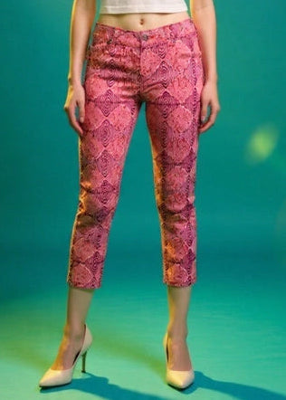 Woman wearing a white top, pink patterned pants, and a hat on a teal background