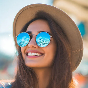 Woman wearing a brown hat and blue sunglasses with a blurred background