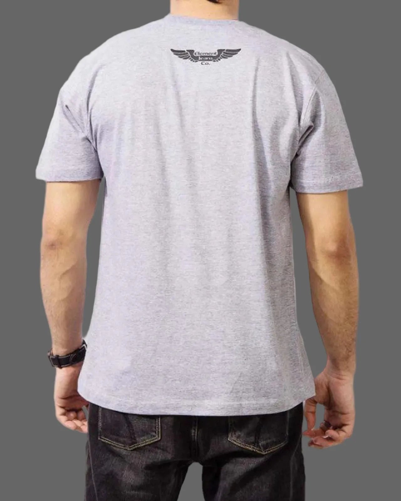Person wearing a gray t-shirt with a logo on the back against a gray background