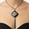 Necklace with a diamond-shaped pendant and tassel on a black mannequin bust.