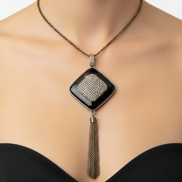 Necklace with a diamond-shaped pendant and tassel on a black mannequin bust.