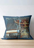 Decorative pillow with a cocktail and cigar design on a wooden surface.