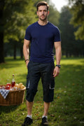 Man standing in a park with a picnic basket and drinks