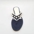 Navy blue sandal with pearl embellishments on a white background