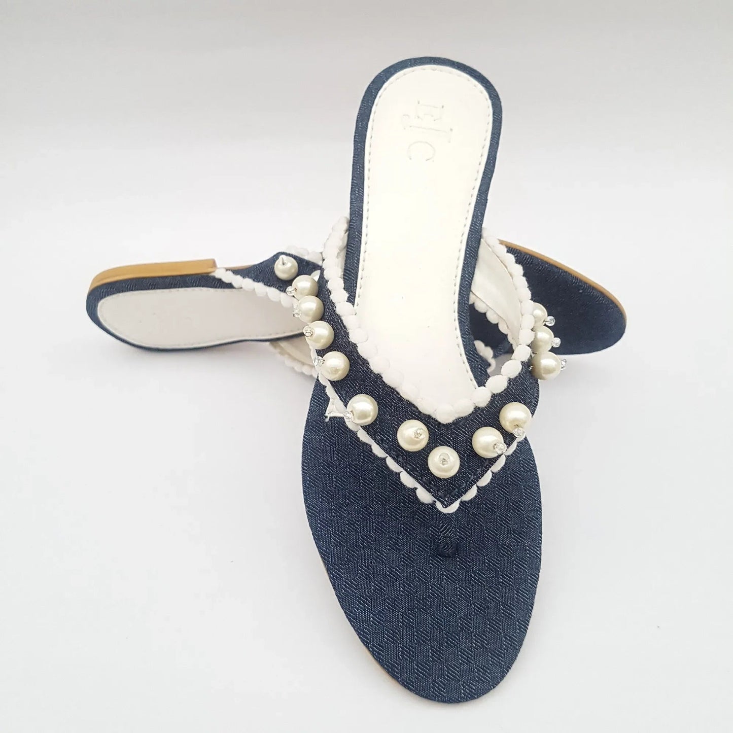 Blue sandal with white pearls on a light gray background