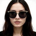 Woman wearing dark sunglasses with a neutral background