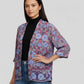 Woman wearing a colorful patterned jacket on a plain background