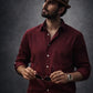 Man wearing a maroon shirt and brown hat against a dark background