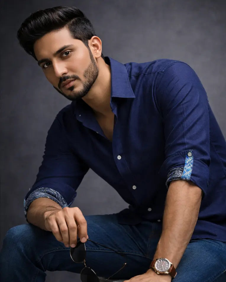 Man wearing a navy blue shirt with rolled-up sleeves against a dark background