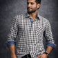 Man wearing a checkered shirt with rolled-up sleeves against a dark background