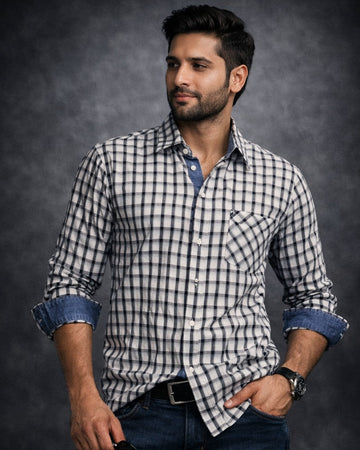 Man wearing a checkered shirt with rolled-up sleeves against a dark background