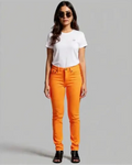 Woman wearing orange pants and a white t-shirt on a gray background