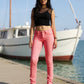 Woman wearing pink jeans and black top by a boat on a dock