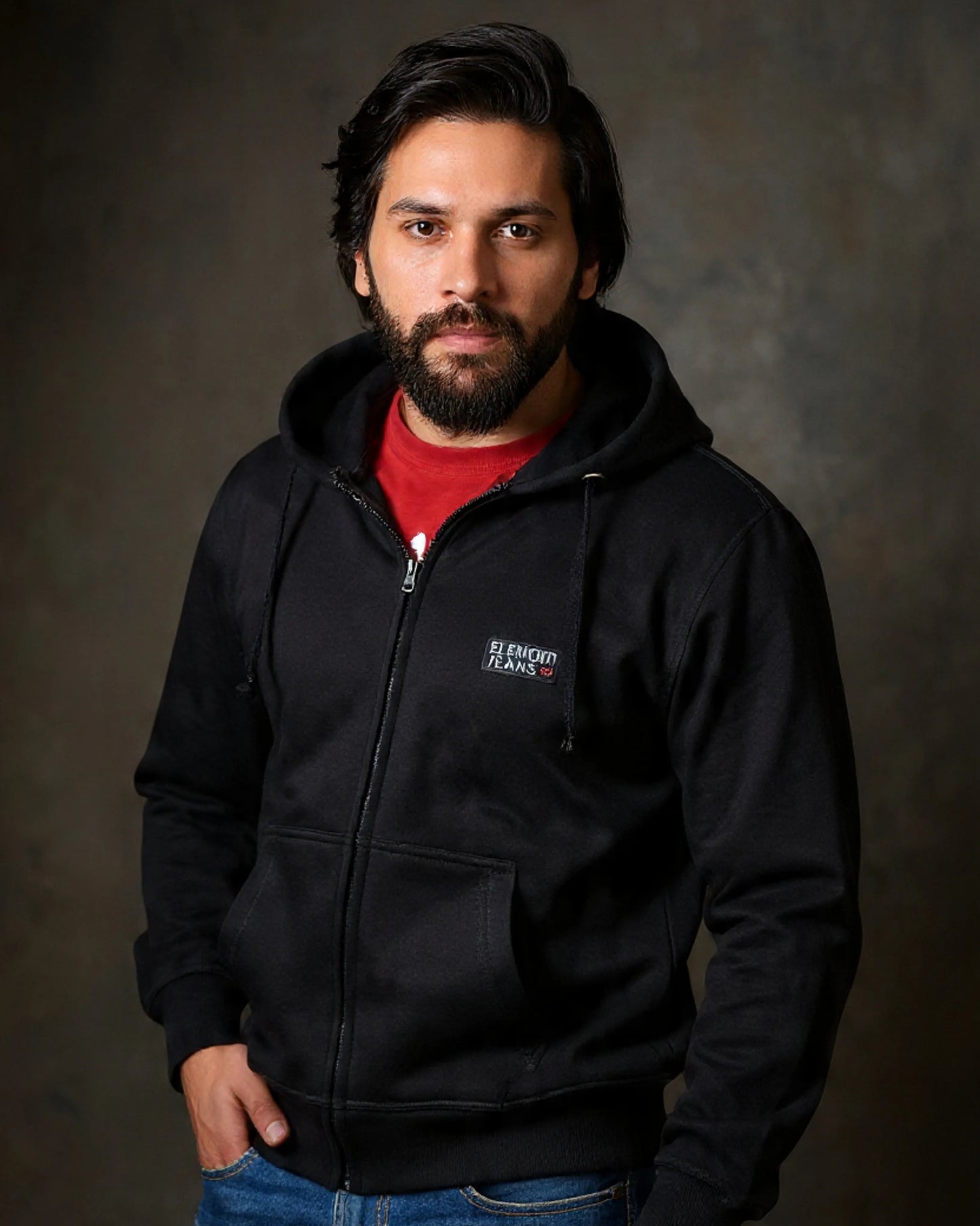 Man wearing a black hoodie with a logo on a dark background