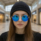 Person wearing blue reflective sunglasses and a black beanie in a mall setting