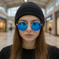 Person wearing blue reflective sunglasses and a black beanie in a mall setting