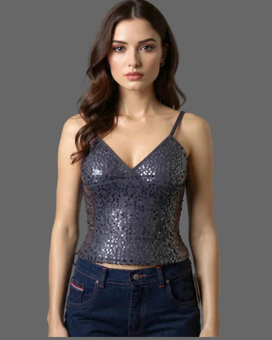 Woman wearing a sequined top and jeans against a neutral background