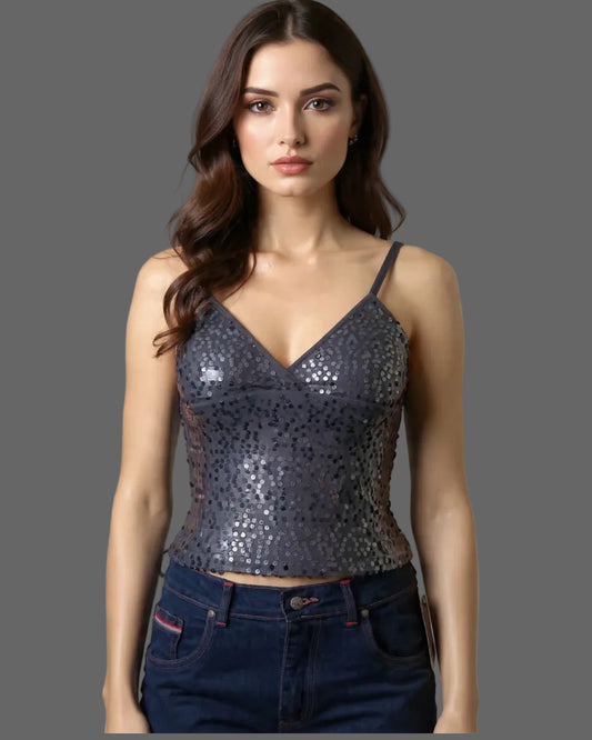 Woman wearing a sequined top and jeans against a neutral background