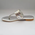 Silver sandal with chain detail on a gray background