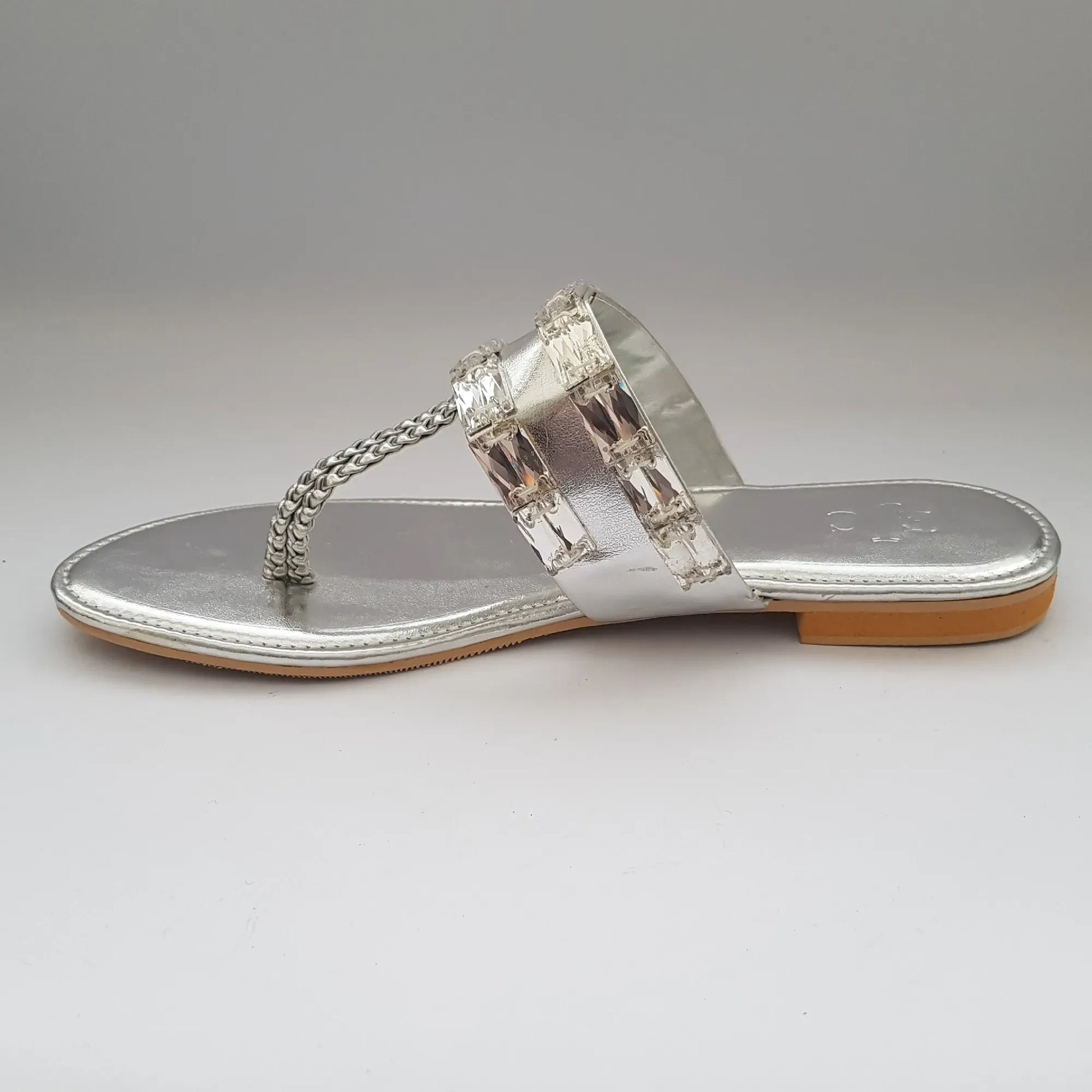 Silver sandal with chain detail on a gray background