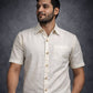Man wearing a white short-sleeve shirt with buttons against a dark background