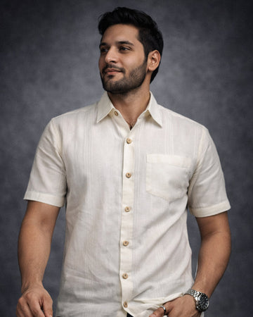 Man wearing a white short-sleeve shirt with buttons against a dark background