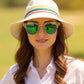 Woman wearing a colorful hat and green sunglasses with a blurred natural background